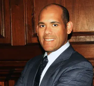 Close up profile image of a man with part of the tie and gray suit jacket visible. 