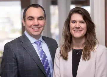 Man and woman wearing suit facing camera