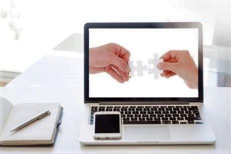 Two hands with puzzle pieces fitting together on a computer screen.