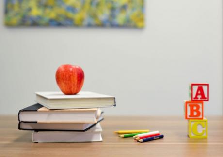 Stack of books with apple on top, colored pencils, and children's blocks with the letters A,B,C stacked up