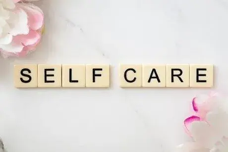 Self Care in letter tiles and 2 flowers
