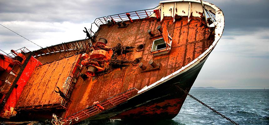 a rusted, shipwrecked vessel resting on its side, jutting into the sky
